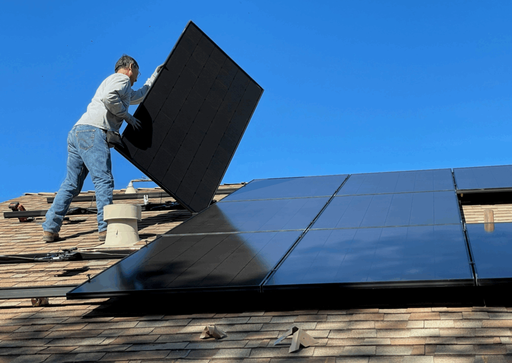 A man installing solar panels on his roof